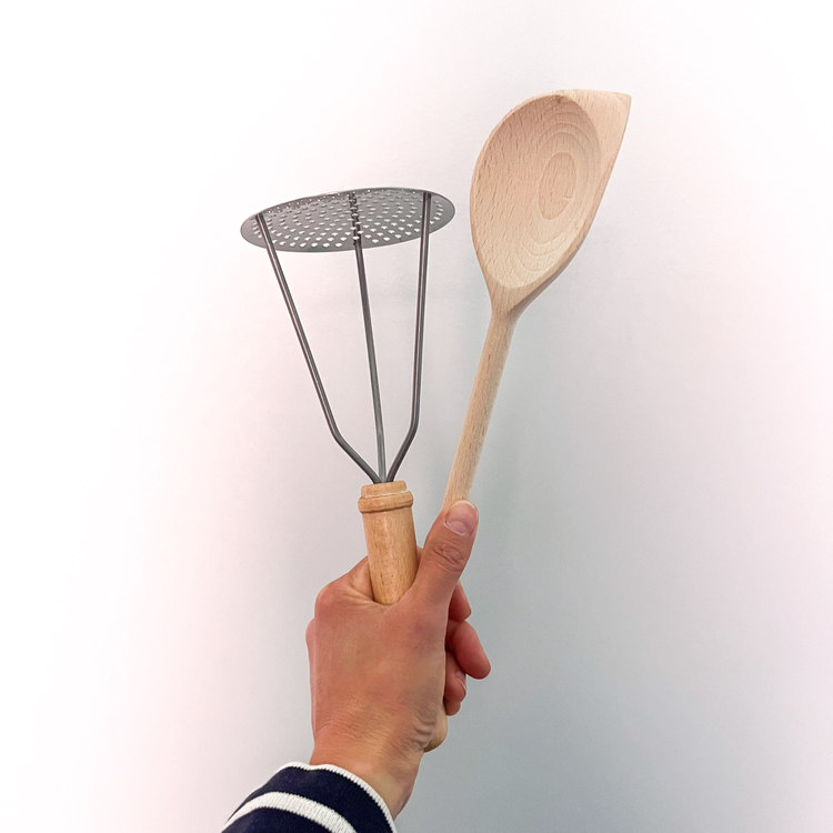 a hand holding kitchen utensils in wood