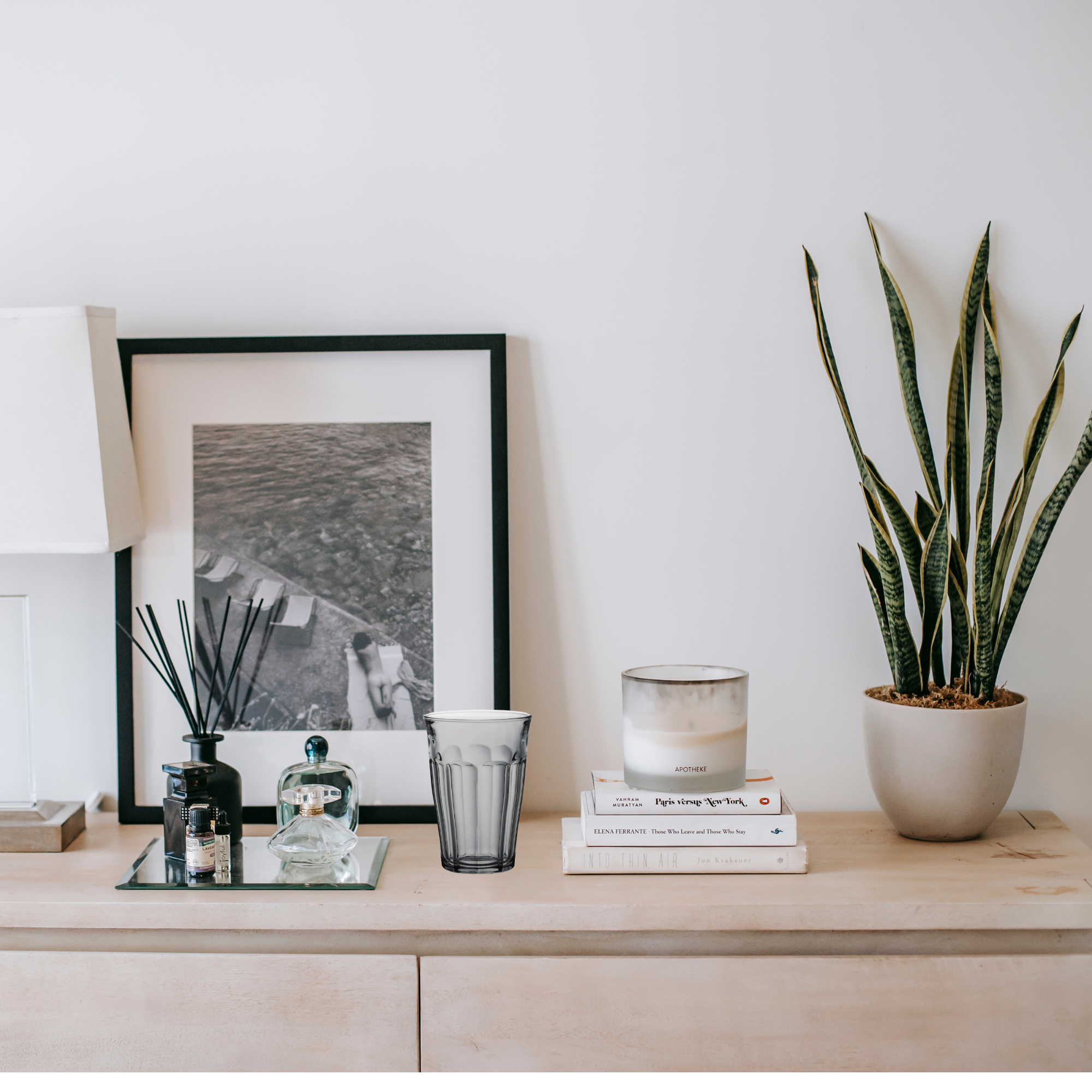 Decorative items around Duralex Picardie Grey Highball Glass colorful tumbler, Made in France, with Decorative items on a wooden surface including a framed picture, candles, books, and a plant.