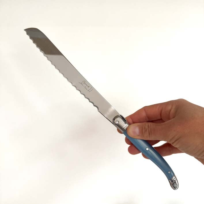Hand holding a Laguiole Blue Bread knife with serrated blade