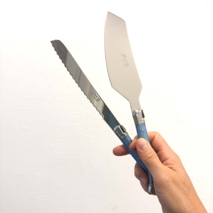 Hand holding Laguiole Blue Bread knife with serrated blade and a cake server