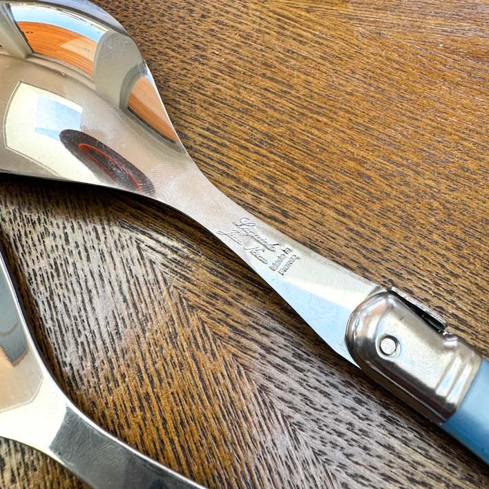 detail of Laguiole Salad Server Set, Pastel Blue Handles on wooden background