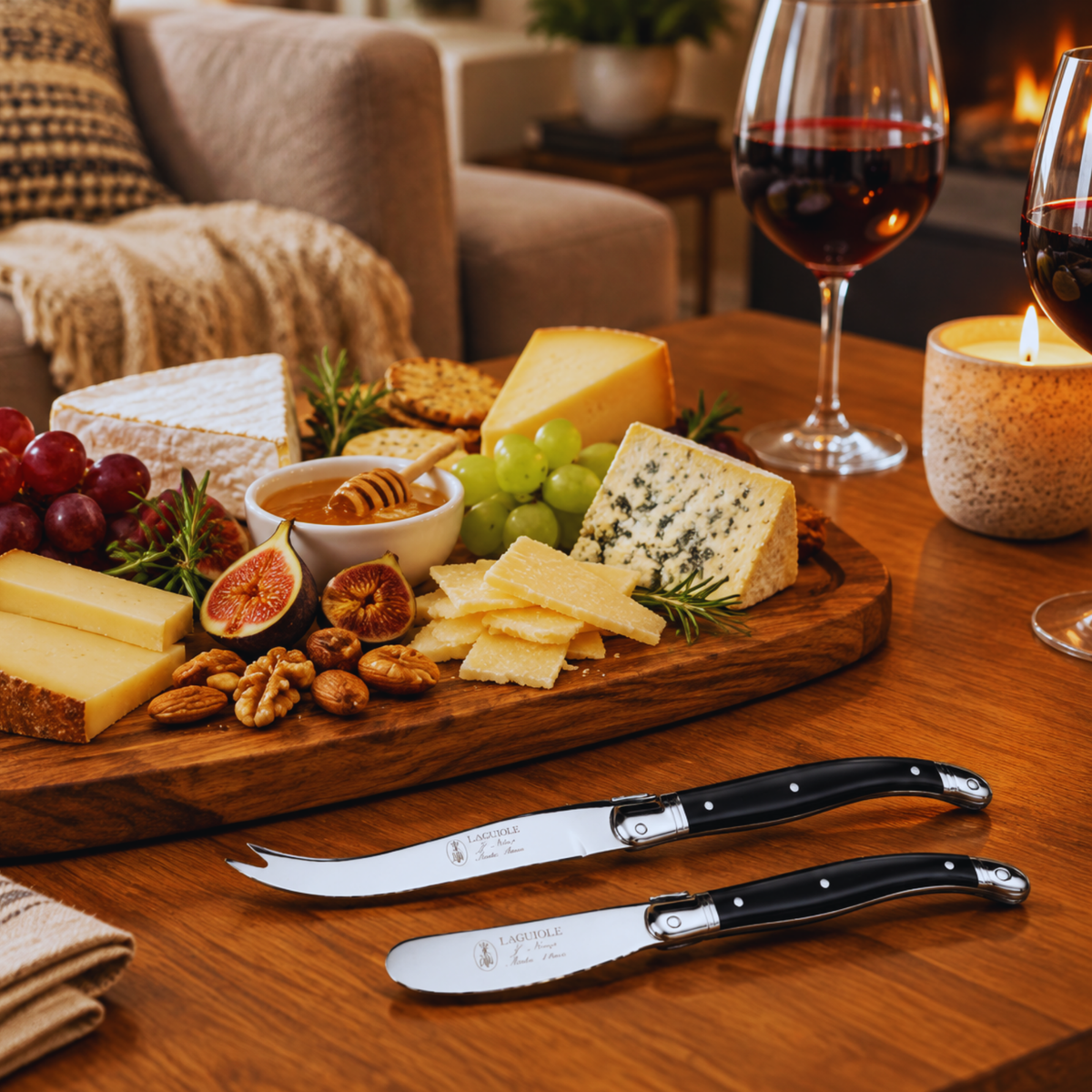 Two Laguiole cheese knives with black riveted handles and polished metal blades with cheese platter