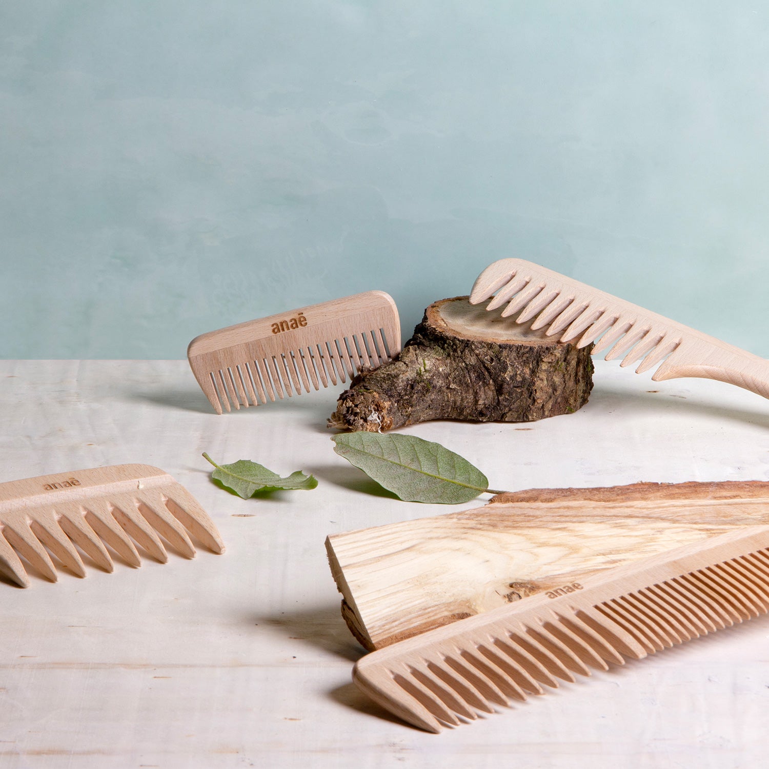 Set of wooden combs on a light surface with a light blue background Clementine Boutique